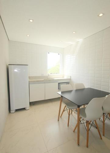 a kitchen with a table and chairs and a refrigerator at Pousada São Gerônimo in Matinhos