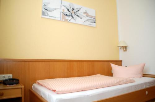 a bedroom with a bed with a pink pillow at Hotel Goldner Anker in Bad Elster