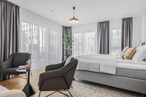 a bedroom with a bed and two chairs and windows at cruwzo I Regensburg Towers - Design Apartments in Regensburg