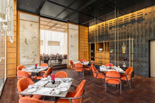 a dining room with tables and orange chairs at The Oberoi Gurgaon in Gurgaon