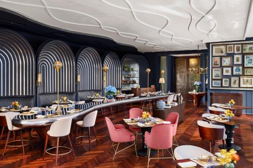 a dining room with tables and pink chairs at The Oberoi Gurgaon in Gurgaon