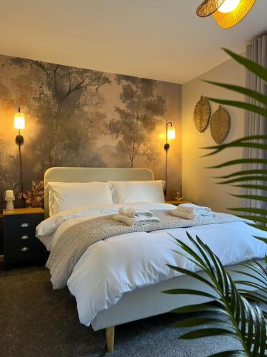 a bedroom with a white bed with a painting on the wall at Stunning and Peaceful 2 bed Flat 10 mins from Stansted Airport in Stansted Mountfitchet