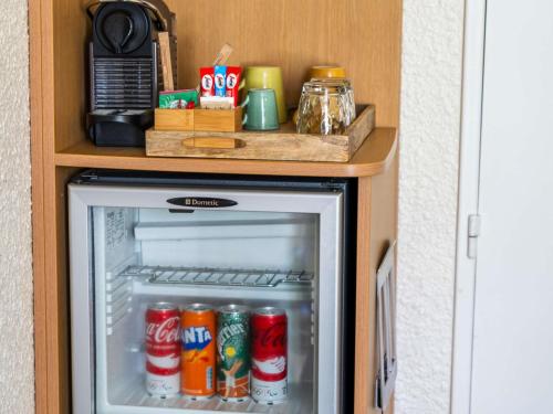 an open refrigerator with cans of coke at Hotel Mercure Château de Fontainebleau in Fontainebleau