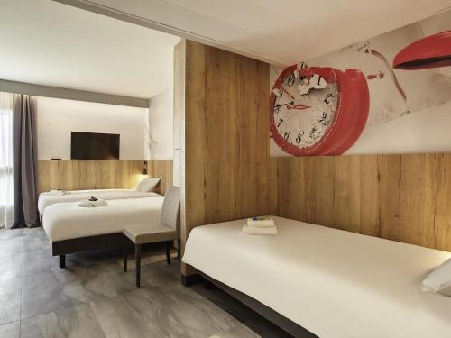 a hotel room with two beds and a clock on the wall at Hotel Mercure Château de Fontainebleau in Fontainebleau