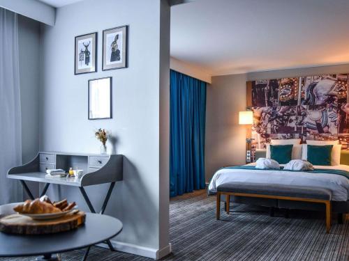 a hotel room with a bed and a table at Hotel Mercure Château de Fontainebleau in Fontainebleau