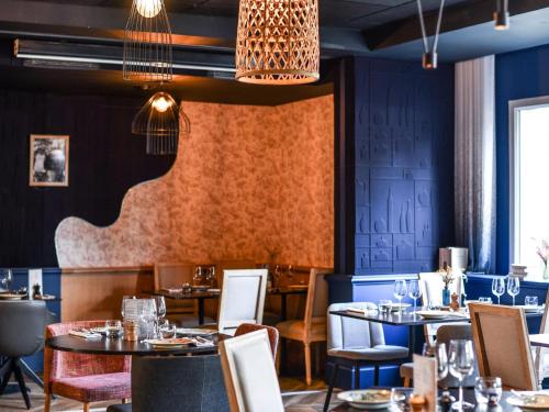 a restaurant with blue walls and tables and chairs at Hotel Mercure Château de Fontainebleau in Fontainebleau