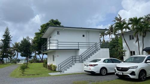 two cars parked in front of a white house at Ocean Villa Guam in Tamuning