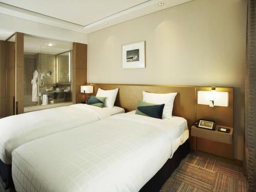 a hotel room with two beds and a bathroom at Novotel Ambassador Seoul Gangnam in Seoul