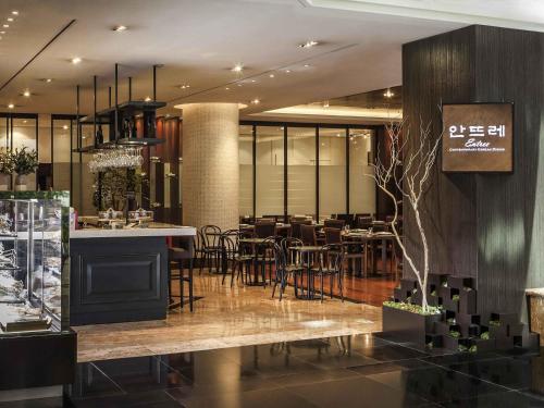 a restaurant with a bar and tables and chairs at Novotel Ambassador Seoul Gangnam in Seoul