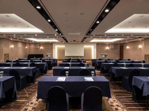a conference room with blue tables and chairs and a screen at Novotel Ambassador Seoul Gangnam in Seoul