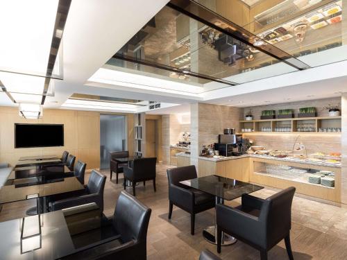a dining room with tables and chairs and a kitchen at Novotel Ambassador Seoul Gangnam in Seoul