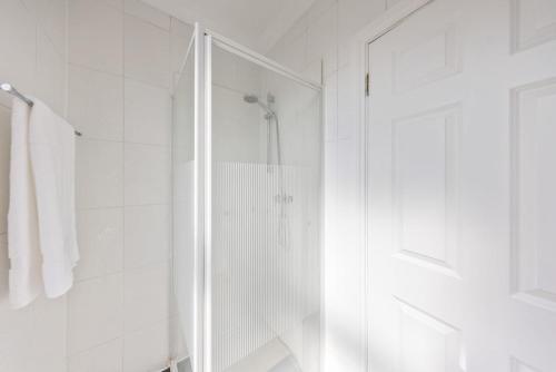 a white bathroom with a shower and a glass door at Modern King Bed WiFi Kitchen Perfect for Long Stay in Gravesend