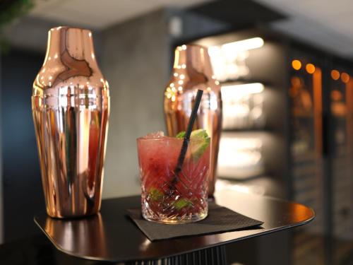 two glass vases sitting on a table with a drink at ibis Aubenas in Aubenas