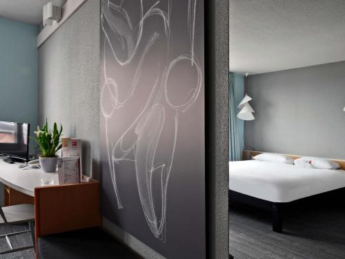 a room with a bed and a desk with a bed sqor at ibis Saint Quentin Basilique in Saint-Quentin