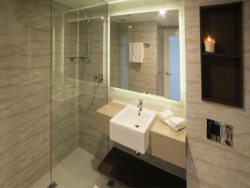 a bathroom with a sink and a glass shower at Novotel Wollongong Northbeach in Wollongong