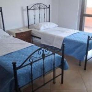 two twin beds in a bedroom with a table at Zostera Apartment in Melito di Porto Salvo