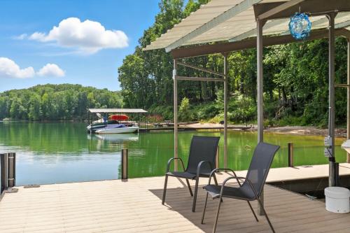 a dock with two chairs and a boat on the water at The Holiday House w Dock in Townville