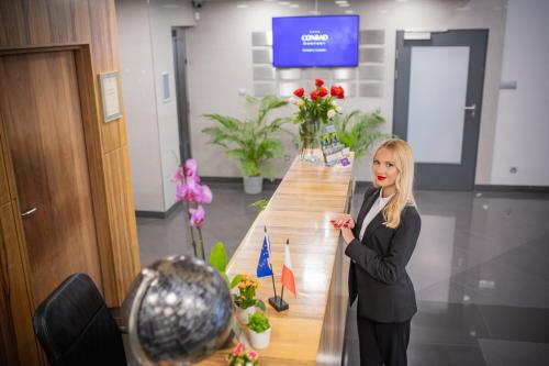 a woman standing next to a long table with flowers at Hotel CONRAD Comfort in Kraków