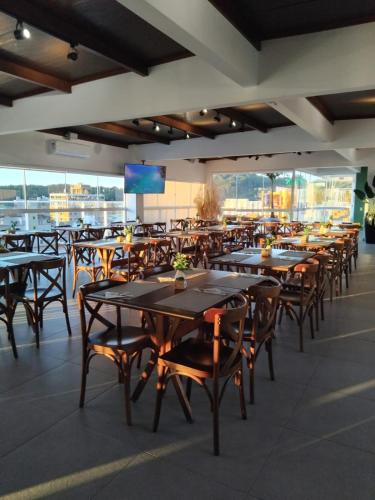 Vila do Centro Apart Hotel في بومبينهاس: غرفة طعام بها طاولات وكراسي وتلفزيون