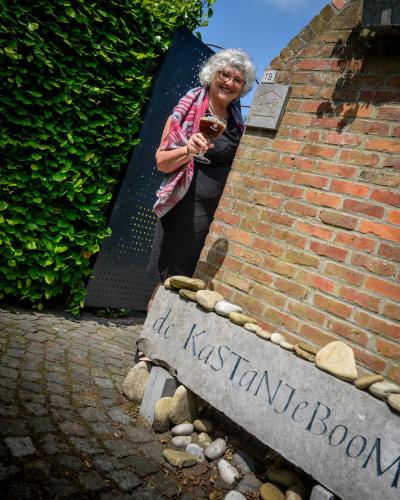 a woman standing next to a brick wall with a sign at B&B De Kastanjeboom in Jabbeke