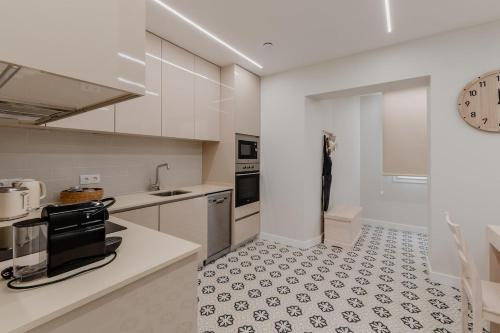 a kitchen with white cabinets and a black and white tile floor at Newest cozy apartment B in Lisbon