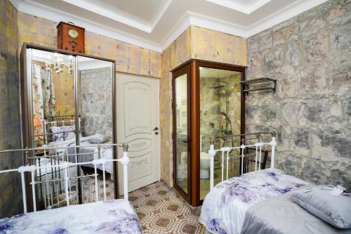 a bedroom with two beds and a stone wall at The Victorian Hotel & Spa Room 3 in Yerevan