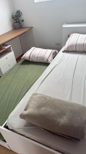 a bedroom with a white bed with a green blanket at Apto novo completo - localização privilegiada in Joinville