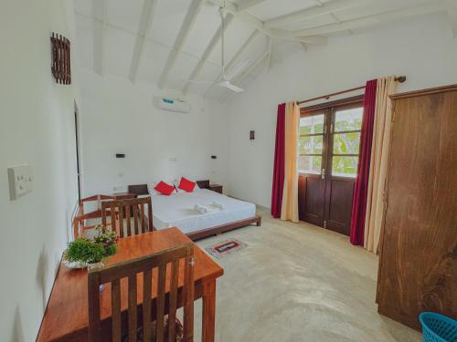 a room with a bed and a table and chairs at Sayuru Villa in Hikkaduwa