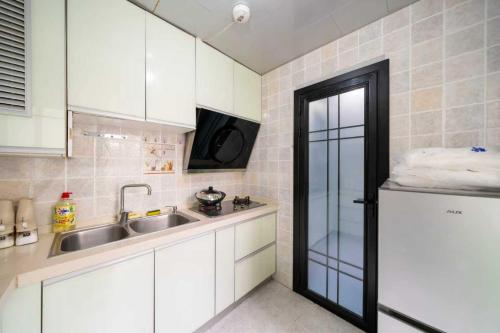 a small kitchen with white cabinets and a sink at 柃居 B&B - Jing'an Temple Branch in Shanghai