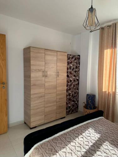 a bedroom with a large wooden cabinet and a bed at Appartement F2 Résidence Belvédère Vue Mer et Piscine Bejaia in Bejaïa