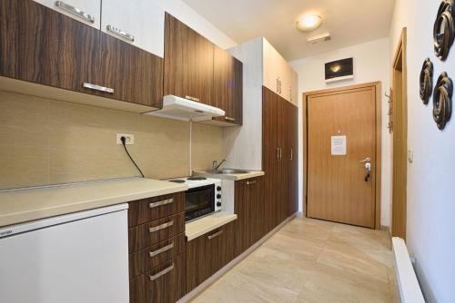 a kitchen with wooden cabinets and a sink and a door at Vila Mina in Zlatibor