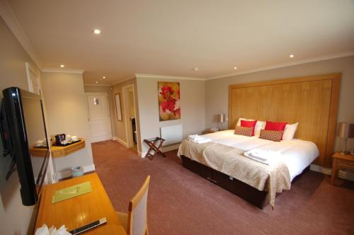 a bedroom with a bed and a desk and a television at Kings Court Hotel in Stratford-upon-Avon