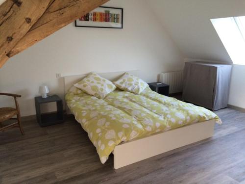 a bedroom with a bed with a yellow comforter at Gîte les petits cris 