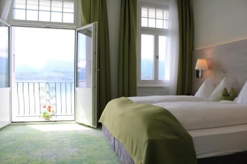 a bedroom with a large bed and a balcony at Hotel Restaurant Bellevue au Lac in Thun