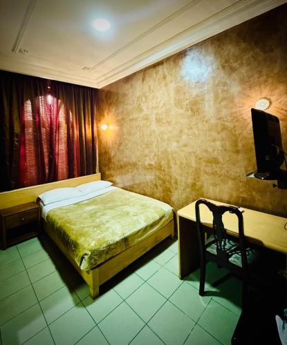 a bedroom with a bed and a desk with a television at Hôtel du Boulevard in Brazzaville
