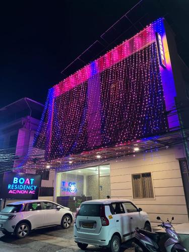 two cars parked in front of a building with christmas lights at Boat Residency in Cochin
