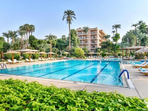 a swimming pool at a resort with palm trees at Pavillon Winter Luxor in Luxor