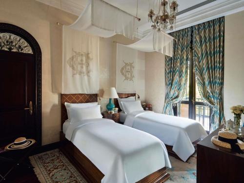 a bedroom with two beds with white sheets and a window at Sofitel Legend Old Cataract in Aswan