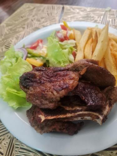 a plate of food with meat and a salad and french fries at Zurich garden lodge benoni in Benoni