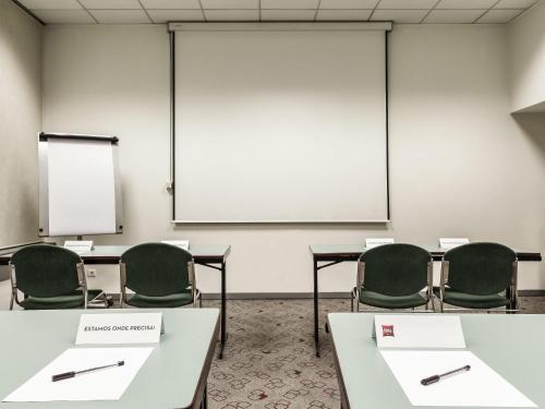 a classroom with tables and chairs and a whiteboard at Hotel Ibis Coimbra Centro in Coimbra