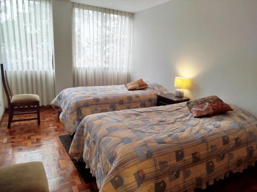 a hotel room with two beds and a chair at Amplio excelente ubicación Calacoto in Irpavi