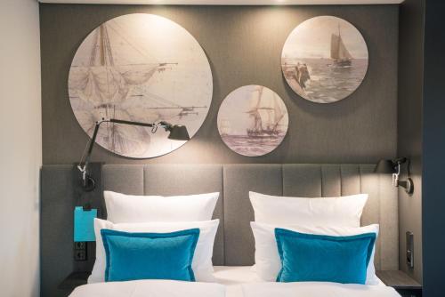 a bedroom with round mirrors above a bed with blue pillows at Motel One Hamburg-Altona in Hamburg