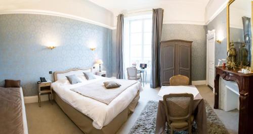 a bedroom with a large bed and a table and chairs at Château de Bellefontaine - Teritoria in Bayeux