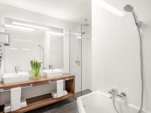 a bathroom with two sinks and a tub and a shower at Nemzeti Hotel Budapest - MGallery Collection in Budapest