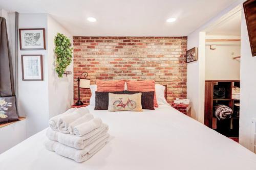 a bedroom with a white bed with a brick wall at Eagle's Landing - Logan Airport in Boston