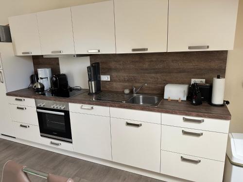 a kitchen with white cabinets and a sink at Ferienwohnung Jasi, OG 95174 in Rhauderfehn