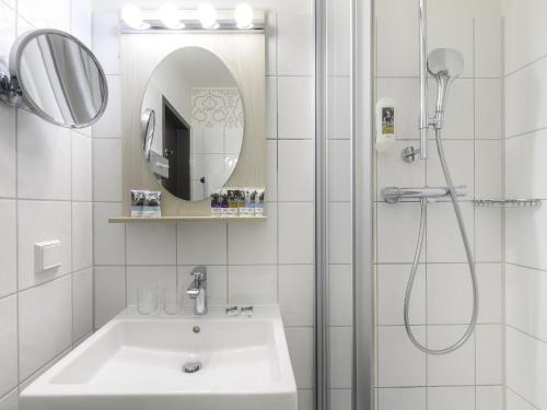 a bathroom with a sink and a shower with a mirror at Mercure München am Olympiapark in Munich