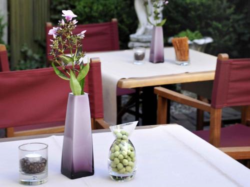 two vases with flowers and grapes on a table at Mercure München am Olympiapark in Munich