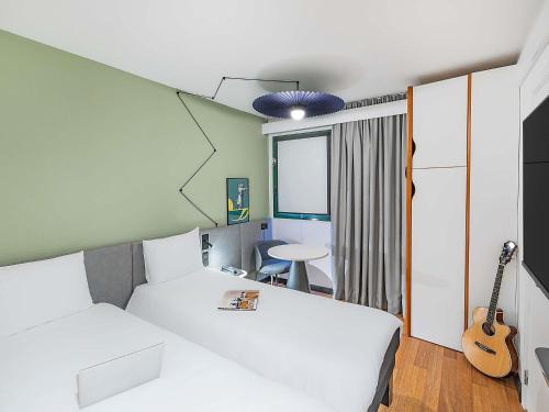 a hotel room with two beds and a guitar at Hotel ibis Evora in Évora