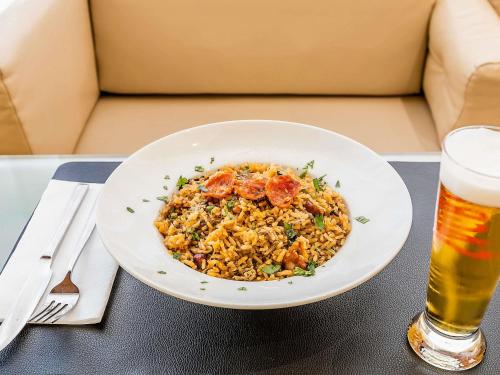 a bowl of food on a table with a glass of beer at Hotel ibis Evora in Évora